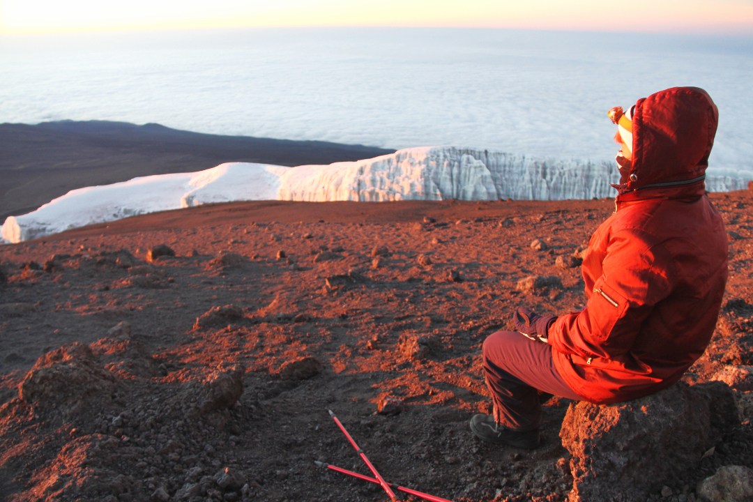 Eine Person sitzt auf einem Felsen auf dem Kilimandscharo