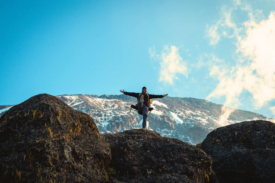 Climber celebrating on Mount Kilimanjaro under a clear blue sky