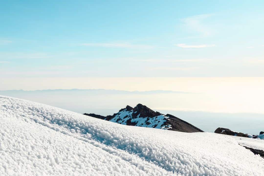 Snow-covered slopes near the summit of Mount Kilimanjaro during sunrise in Tanzania