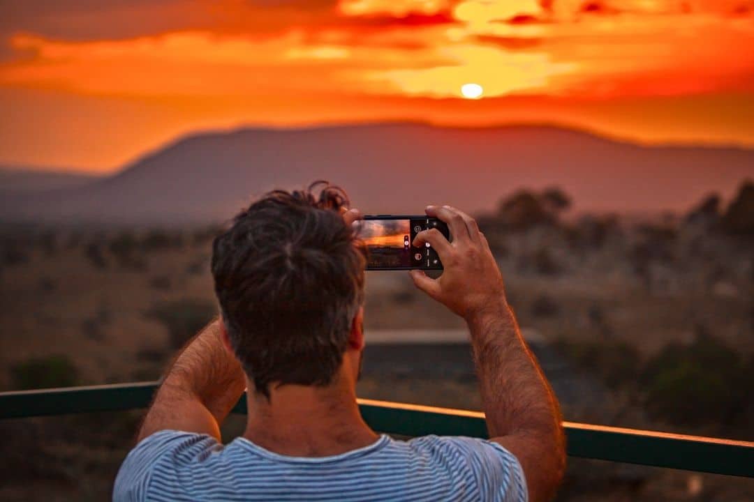 Traveler photographing a glowing African sunset during a safari in Tanzania